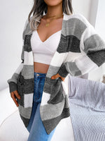 Woman wearing a striped cardigan over a white top and blue jeans, sitting on a couch.