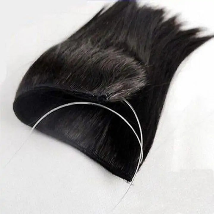 Close-up of a black hair topper or extension piece with a base and two thin clear/white attachment strings.