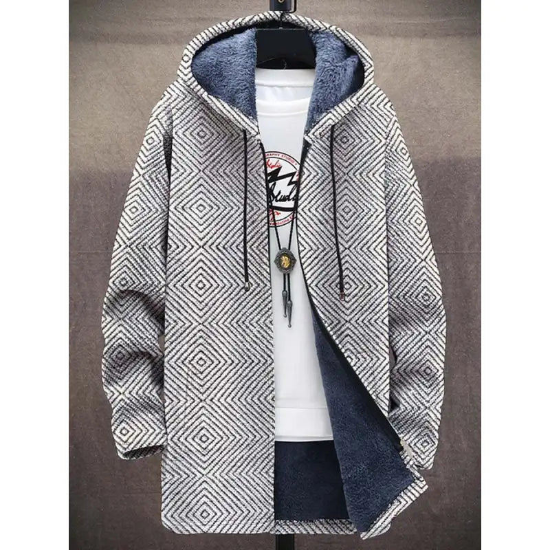 A modern fleece-lined hoodie featuring a geometric pattern in black and white. The symmetrical diamond shapes create an eye-catching design. The hoodie is lined with soft, deep blue plush fabric for warmth and comfort. It has black drawstrings and is styled with a white inner shirt and a pendant necklace for a trendy, layered look.