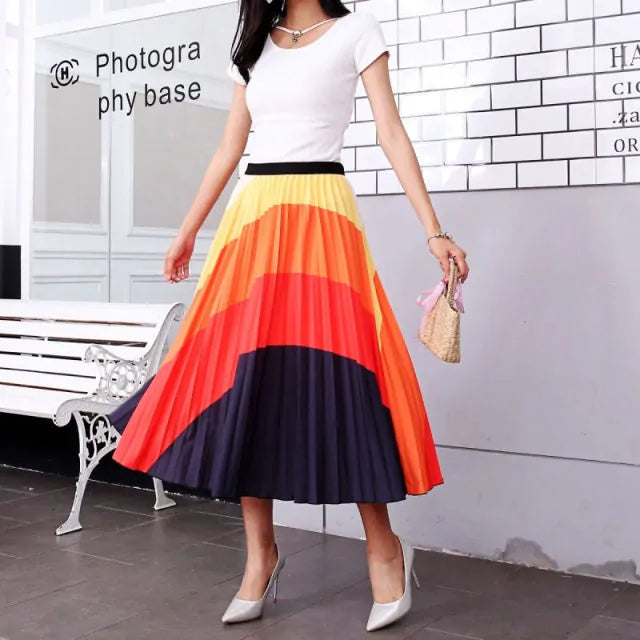 Pleated midi skirt with a gradient design, transitioning from dark black at the waistband to a soft blush pink at the hem, hanging on a black clothing rack next to a vintage-style camera.