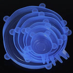 Set of translucent blue silicone stretch lids in multiple sizes, stacked together on a black background, each with small pull tabs around the edge.