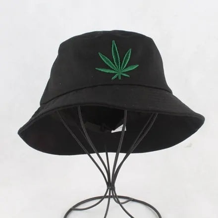 Black bucket hat with a green leaf embroidery on the front, displayed on a wire stand against a white background.