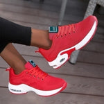 Bright red lace-up sneakers with breathable knit upper, thick white cushioned soles, and visible air-cushion heels, shown worn with black leggings.