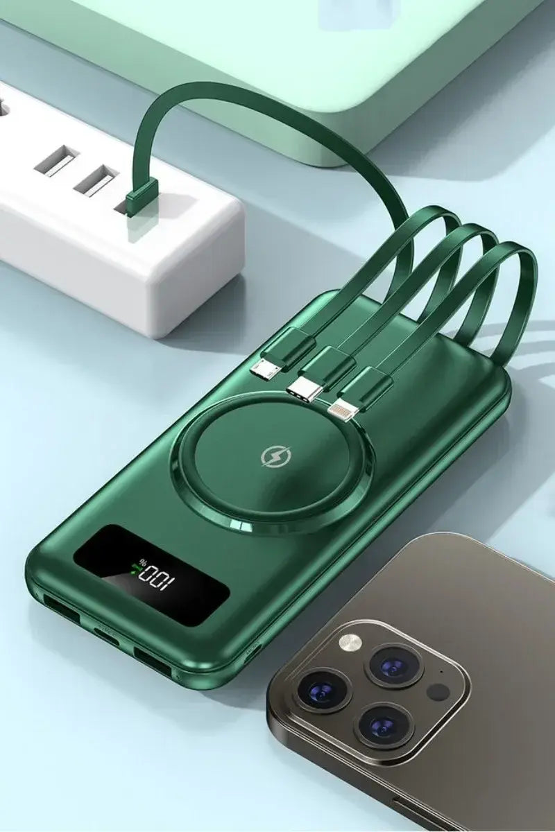 Green power bank with a digital display and built-in charging cables (multiple connector types) plugged into a wall adapter, shown on a desk next to a smartphone.