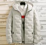 A black puffer jacket with a hood is displayed on a hanger over a white collared shirt with a red horizontal stripe. The jacket has a quilted design with rectangular stitching patterns and features a zipper closure. The shirt underneath is slightly visible, adding contrast. The background consists of a neutral-toned fabric backdrop, with wooden shelves on the left and a small green plant on the right