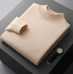 A neatly folded beige knitted sweater with a ribbed high collar and cuffs, placed on a dark grey surface. Beside the sweater, a classic wristwatch with a black leather strap and a silver dial is positioned, adding a touch of elegance to the composition.