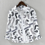 This is a stylish long-sleeve button-up shirt with a white base and an artistic abstract print in gray tones. The lightweight, textured fabric gives it a breezy, casual feel, making it perfect for layering over a t-shirt, as shown in the image. It also features a front pocket with a small label detail that adds a modern touch.