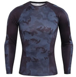 A long-sleeved athletic compression shirt with a gray, black, and white camouflage pattern on the front and sleeves. The shirt has black side panels and raglan-style sleeves, giving it a sporty and fitted design. The fabric appears to be stretchy and moisture-wicking, suitable for workouts or outdoor activities.