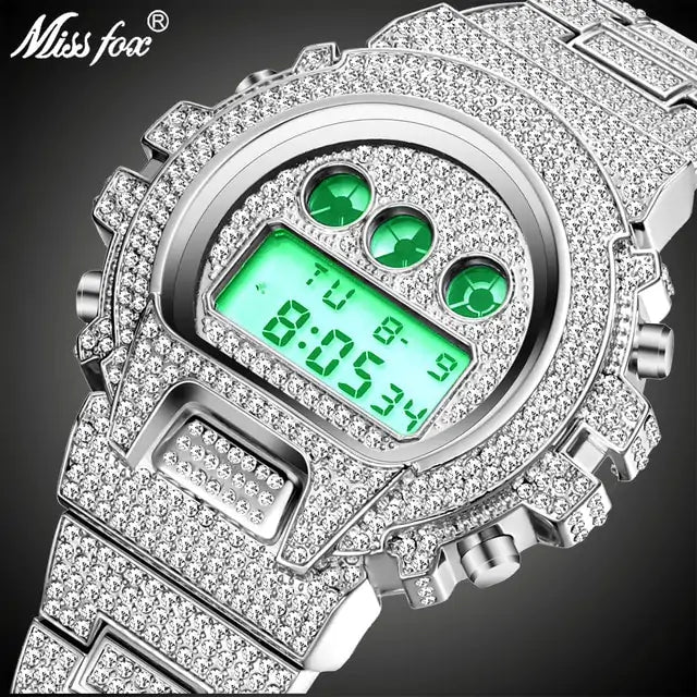 Close-up of a silver-tone digital wristwatch covered in rhinestones, with a green backlit display and three green accent circles above it; “Miss fox” logo appears in the top left on a dark background.