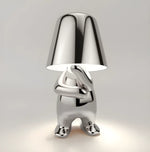 Silver novelty table lamp shaped like a standing character holding a lampshade.
