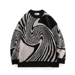 A studio product image of an oversized knit crewneck sweater on a white background, featuring a bold black, white, and gray abstract swirl/optical-illusion pattern with ribbed cuffs, collar, and hem.