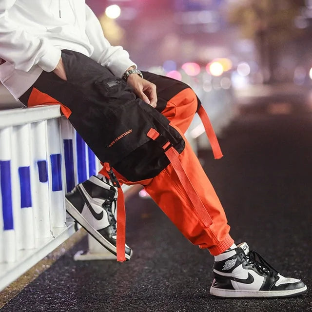 Black and orange cargo joggers with strap details.
