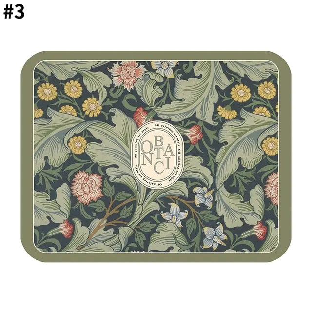 Rectangular decorative mat with a sage green border, vintage botanical floral pattern in muted greens and yellows, and a central oval emblem featuring stylised lettering.