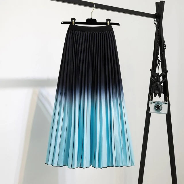 Pleated midi skirt with a gradient design, transitioning from dark black at the waistband to a soft blush pink at the hem, hanging on a black clothing rack next to a vintage-style camera.