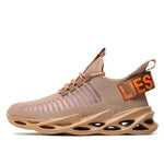 A beige slip-on knit sneaker with a sock-like upper, lace-up front, and a pull tab at the heel. It features orange text detailing on the side strap and a sculpted cutout sole that gives the shoe a sporty, modern look.