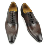 A pair of elegant burgundy leather loafers with a glossy finish. The shoes feature gold-toned metal horsebit detailing across the uppers and are displayed with wooden shoe trees inserted. They have a sleek, elongated silhouette with subtle stitching along the toe cap. The loafers are placed on a dark surface, partially framed by a wooden picture frame, emphasizing their classic and sophisticated style.