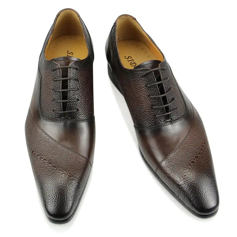 A pair of elegant burgundy leather loafers with a glossy finish. The shoes feature gold-toned metal horsebit detailing across the uppers and are displayed with wooden shoe trees inserted. They have a sleek, elongated silhouette with subtle stitching along the toe cap. The loafers are placed on a dark surface, partially framed by a wooden picture frame, emphasizing their classic and sophisticated style.