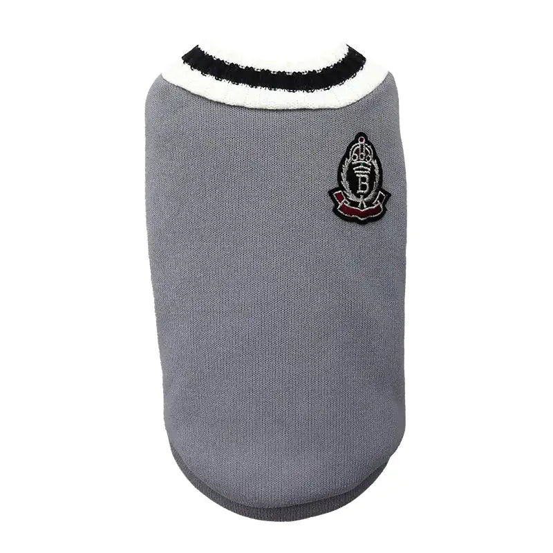 A stylish gray pet sweater with a white and black ribbed collar, featuring a small embroidered crest patch on the upper back.