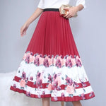 Pleated midi skirt with a gradient design, transitioning from dark black at the waistband to a soft blush pink at the hem, hanging on a black clothing rack next to a vintage-style camera.