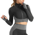Woman wearing a seamless, textured long-sleeve athletic zip-up top in a light pink and peach gradient, featuring a high collar and thumb holes.