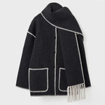 Dark wool coat with white blanket stitch trim, featuring front buttons, large patch pockets, and an attached matching scarf with fringe detailing draped over the shoulder. The coat is displayed against a plain white background.