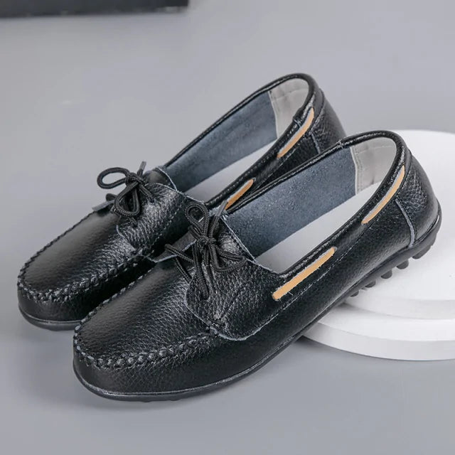 Black leather loafers with bow ties, moc-toe stitching, and flexible driving-style soles.