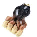 Ombre wavy hair extension bundles tied at the top, with dark black roots blending into warm brown mid-lengths and light blonde ends, styled in large loose curls on a white background.
