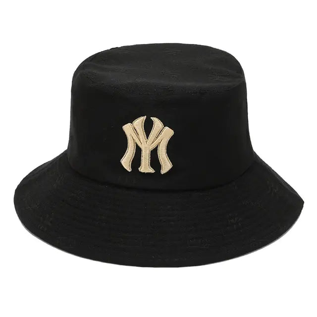 Black bucket hat with a wide downward brim and embroidered beige “NY” logo on the front.