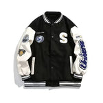 Black and white varsity jacket with striped ribbed trims, snap-button front and embroidered patch details.
