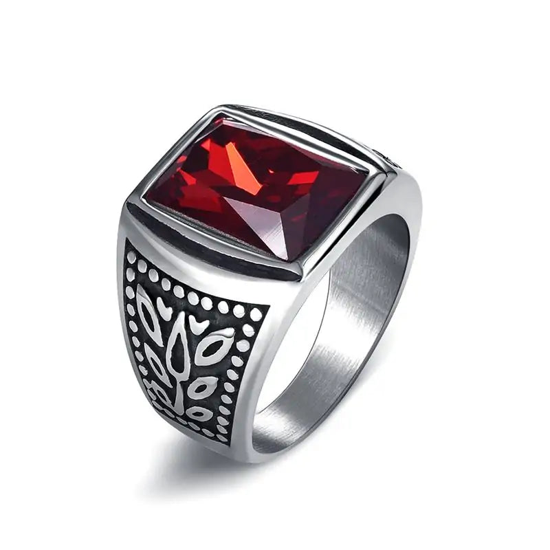 Silver-toned signet-style ring with a large square-cut red gemstone and engraved black-and-silver detailing on the sides, shown on a white background.