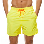Neon yellow swim shorts with an elastic waistband, orange drawstring, and side pockets.