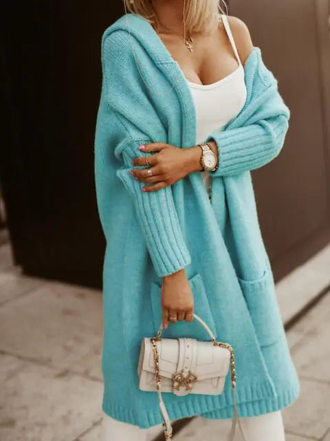 Person wearing a light blue cardigan holding a white handbag.