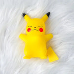 Cute Pikachu figure made of yellow soft plastic, with closed eyes and a smiling expression, set against a fluffy white background.