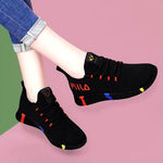 A pair of stylish mesh sneakers worn with jeans. The shoes feature colorful embroidered details The sneakers have a sleek, breathable design and a casual, trendy aesthetic.