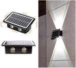 Product collage of a solar-powered outdoor wall light: a small rectangular solar panel lamp with two LED lenses and labeled dimensions, plus an example installed on a wall projecting bright up-and-down beams at night.