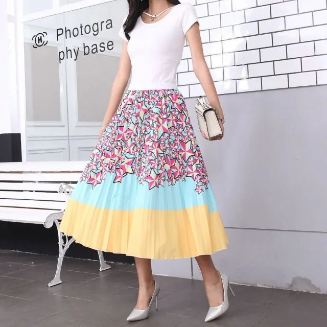 Pleated midi skirt with a gradient design, transitioning from dark black at the waistband to a soft blush pink at the hem, hanging on a black clothing rack next to a vintage-style camera.