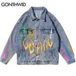 A light blue oversized denim jacket with a button-front closure, pointed collar, flap chest pockets, and side welt pockets. It features colorful paint-splatter accents and a bold flame graphic across the front for a graffiti-inspired streetwear look.