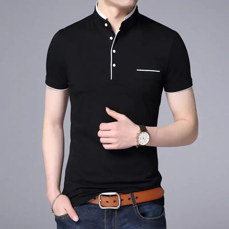 A stylish short-sleeved polo shirt with a mandarin collar, white trim detailing, and a partial button-up design. The shirt features a small decorative white-lined pocket on the left chest. The model is wearing dark jeans, a brown leather belt, a wristwatch, and a bracelet, posing casually with one hand resting on the belt buckle
