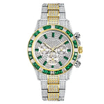 A luxurious, diamond-encrusted watch with a silver and gold bracelet. The watch features large green gemstones around the dial and intricate detailing, creating a flashy and opulent look.