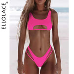 Model wearing a hot pink bikini with cutouts and crisscross straps on the sides, posed on a beach.