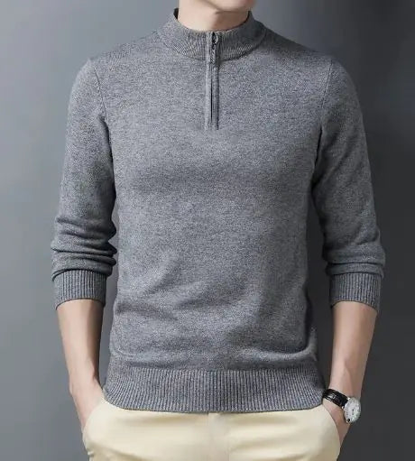 A sleek slim-fit sweater with a quarter-zip collar, worn by a male model against a neutral gray background. The sweater features ribbed cuffs and a ribbed hem for a snug and polished fit. The model pairs it with light-colored trousers and a silver wristwatch, creating a refined and sophisticated look.