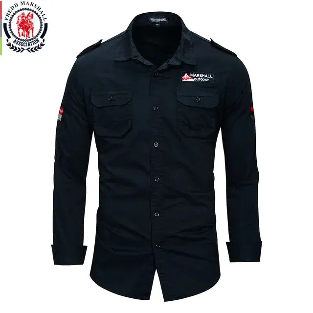 A military-inspired khaki long-sleeve button-up shirt with black buttons. The shirt features two front chest pockets with flap closures, a 'Marshall Guardian' patch on the right chest, and a red and black chevron patch on the left sleeve. The rugged design and structured fit give it a tactical, adventure-ready look