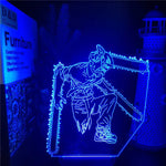 A glowing blue anime-style LED acrylic lamp featuring a character with chainsaw-like blades extending from the head and arms, displayed on a dark tabletop in a dimly lit room.